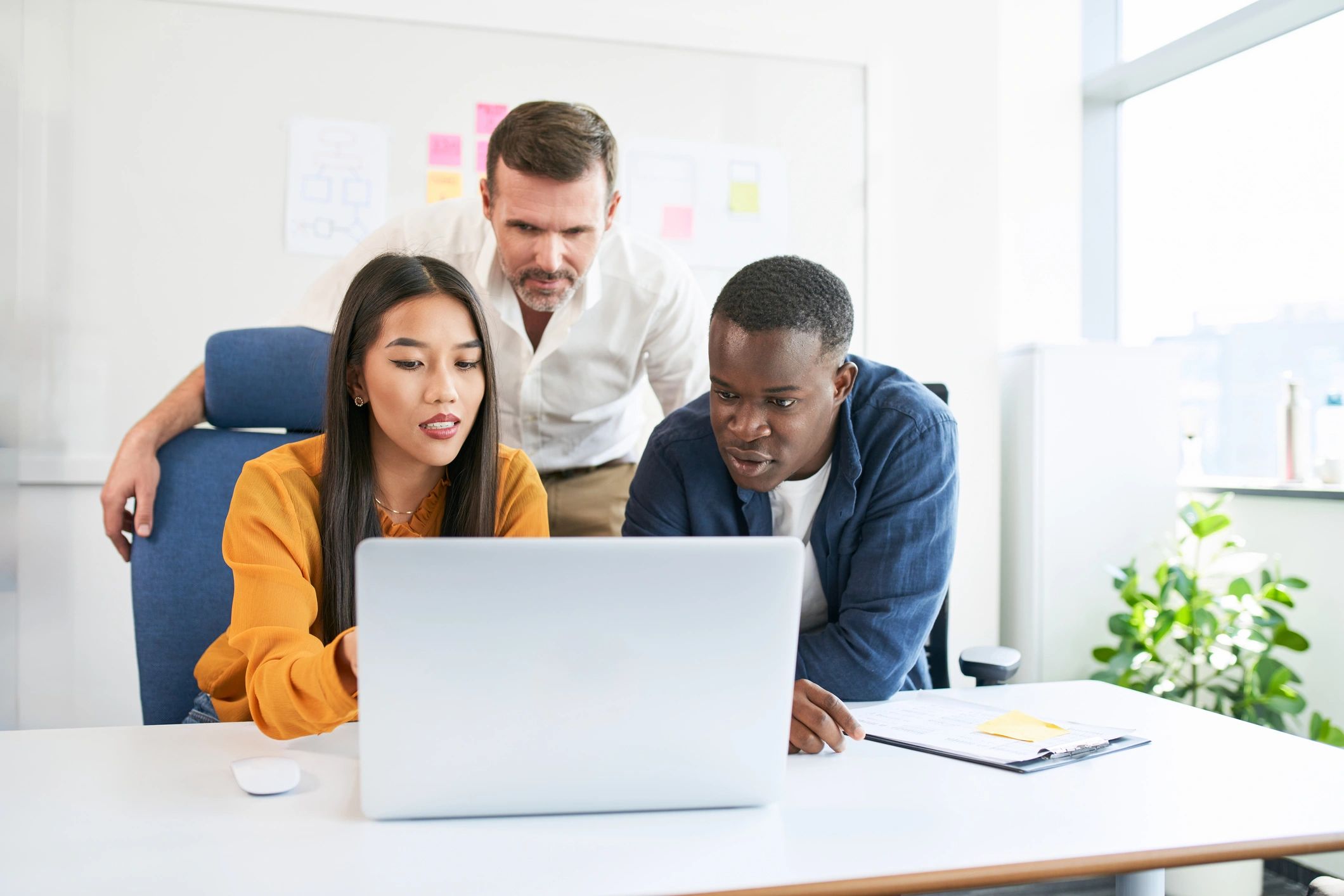 Business professionals collaborating around a laptop in a modern office
